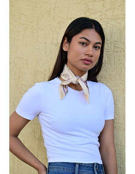 Femme portant le petit foulard Anastase latte 50x50 cm noué autour du cou.