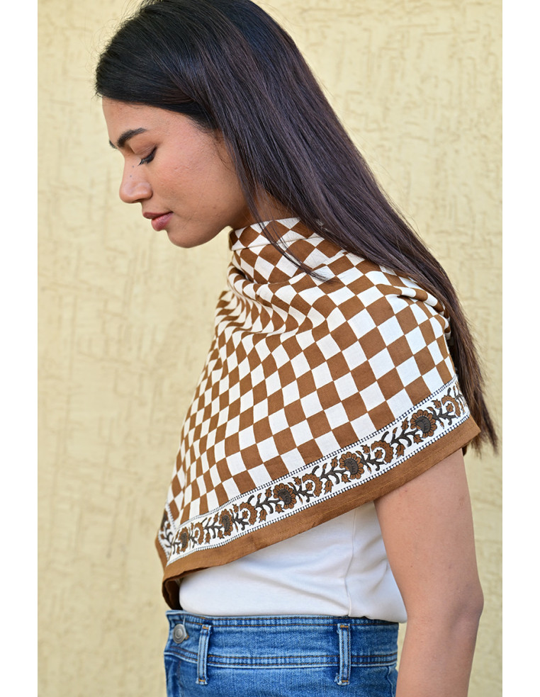 Gros plan sur la bordure florale imprimée au tampon de bois sur fond damier.