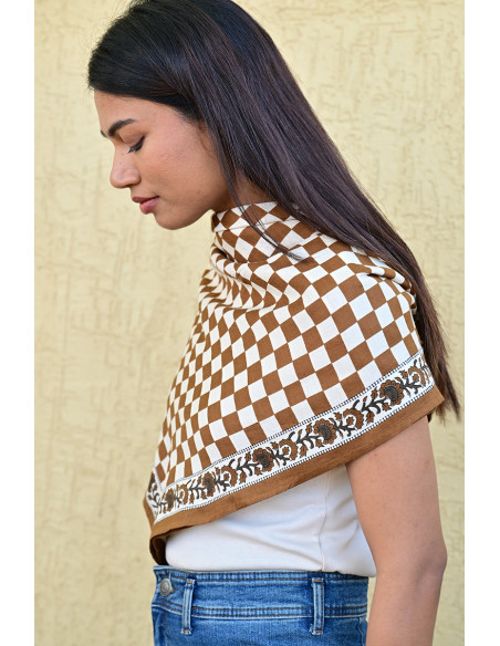 Gros plan sur la bordure florale imprimée au tampon de bois sur fond damier.