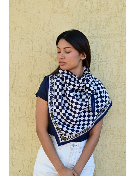 Femme portant le grand foulard Checks Bleu Marine 100x100 cm noué autour du cou.