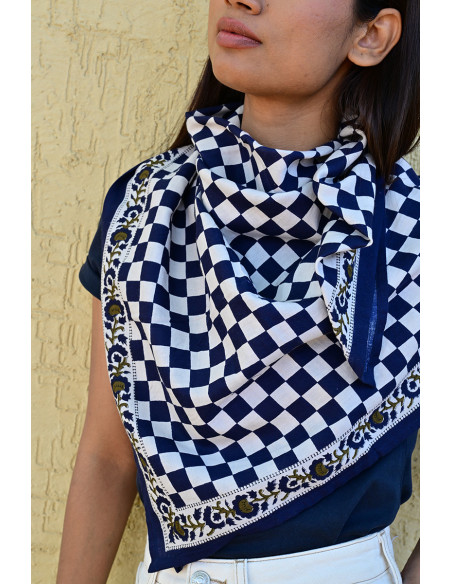 Femme portant le grand foulard Checks Bleu Marine 100x100 cm noué autour du cou.