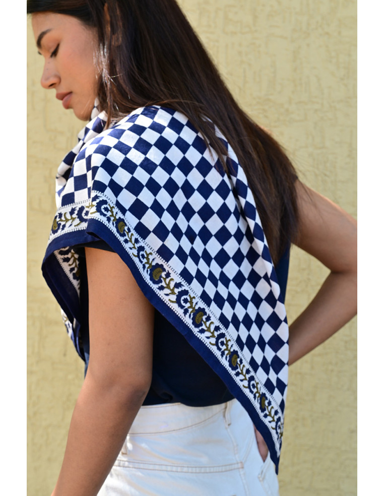 Gros plan sur la bordure florale imprimée au tampon de bois sur fond damier.