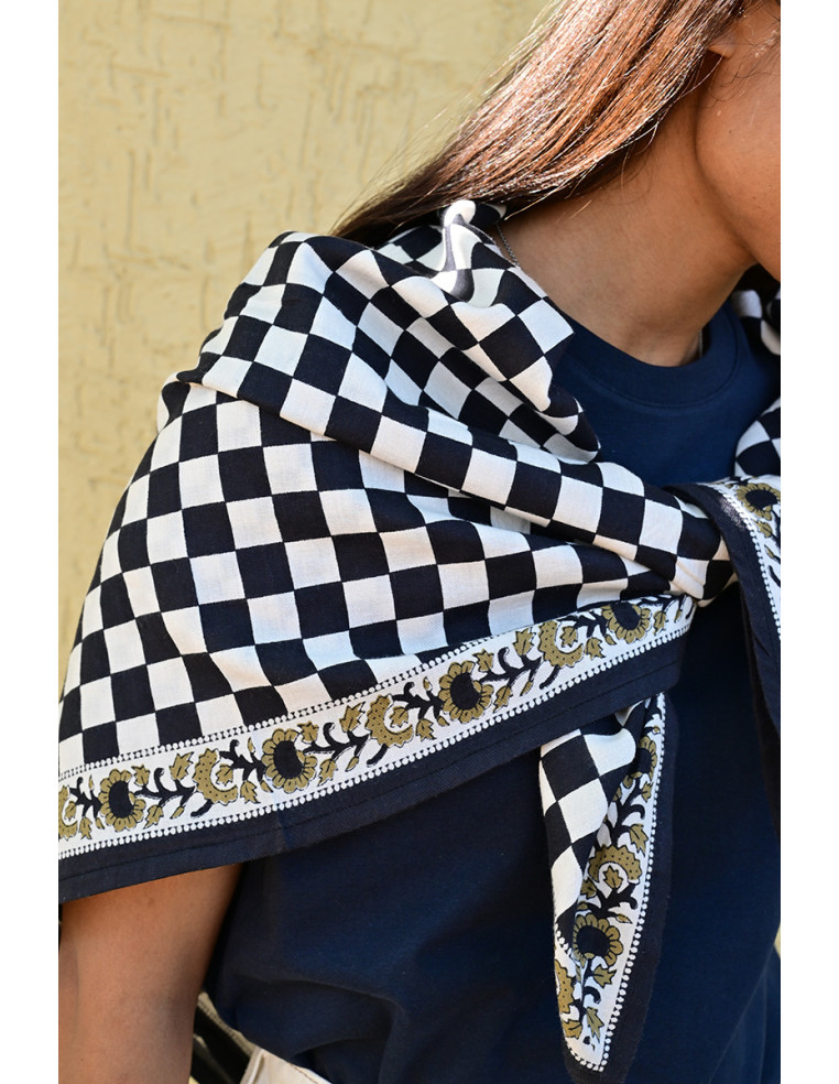 Gros plan sur la bordure florale imprimée au tampon de bois sur fond damier.