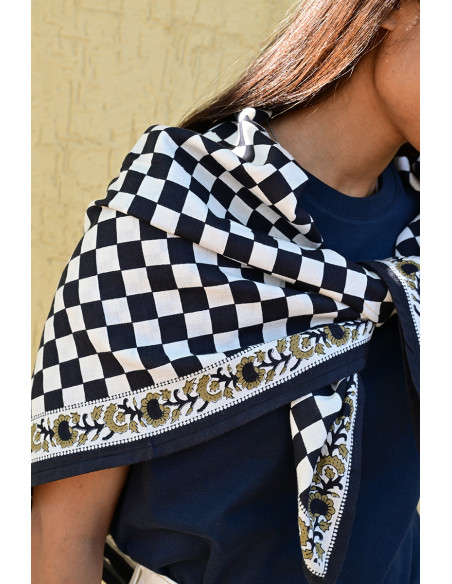 Gros plan sur la bordure florale imprimée au tampon de bois sur fond damier.