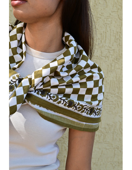 Gros plan sur la bordure florale imprimée au tampon de bois sur fond damier.