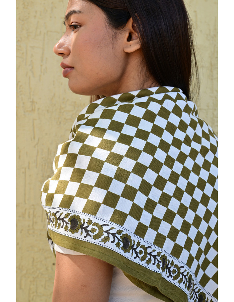 Gros plan sur la bordure florale imprimée au tampon de bois sur fond damier.