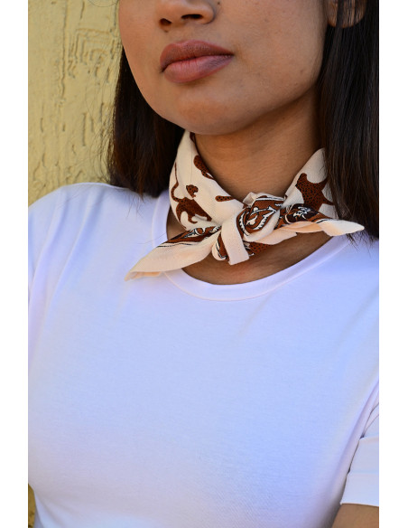 Femme portant le petit foulard Fauve Latte 50x50 cm noué autour du cou.