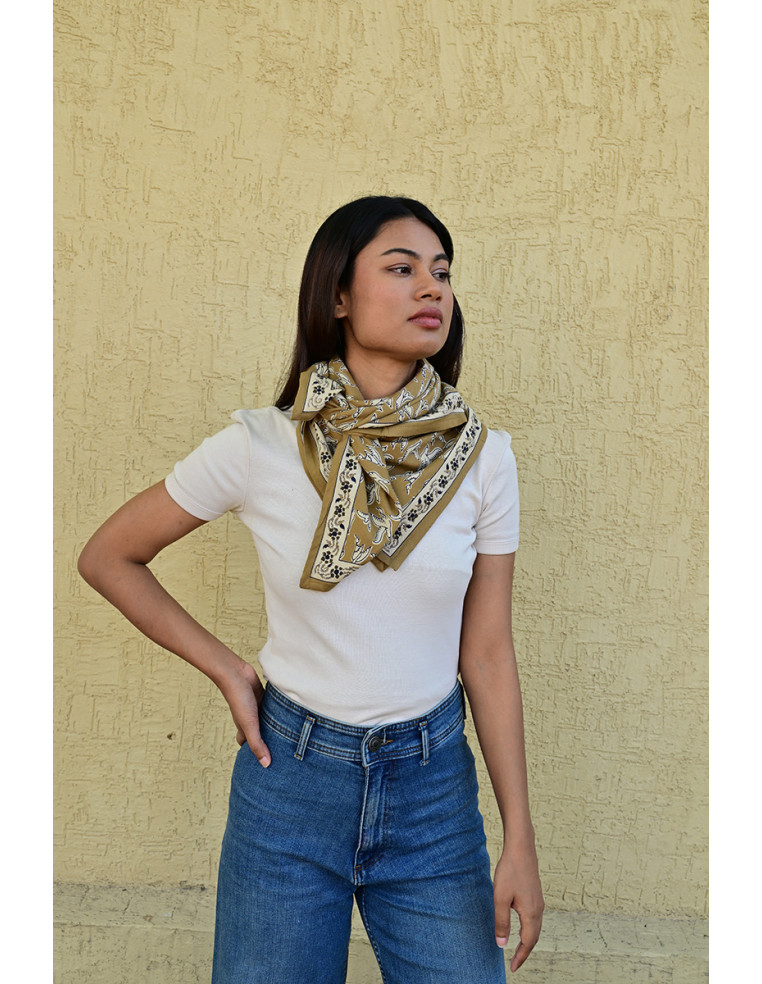 Femme portant le grand foulard Mercure Bistre 100x100 cm noué autour du cou.