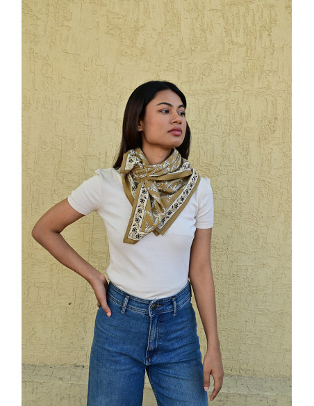 Femme portant le grand foulard Mercure Bistre 100x100 cm noué autour du cou.