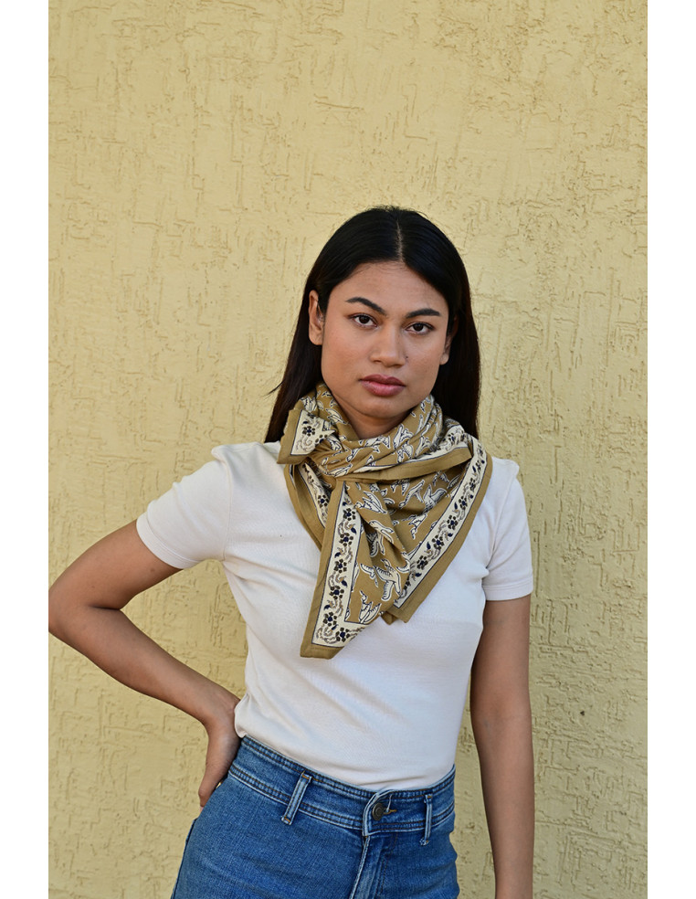 Femme portant le grand foulard Mercure Bistre 100x100 cm noué autour du cou.