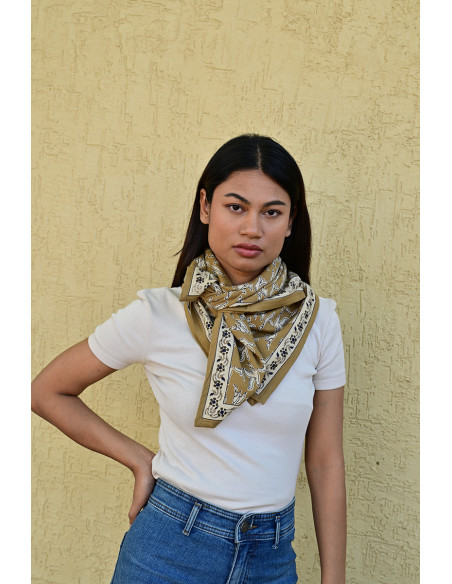 Femme portant le grand foulard Mercure Bistre 100x100 cm noué autour du cou.