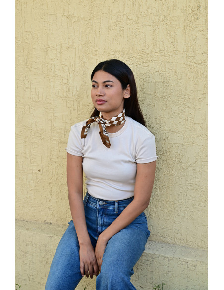 Femme portant le petit foulard Checks Bistre 50x50 cm noué autour du cou.