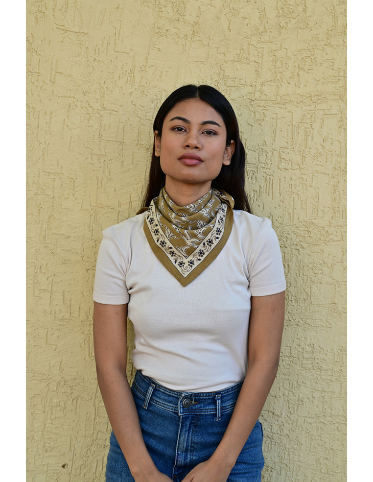 Femme portant le petit foulard Mercure Bistre 50x50 cm noué autour du cou.