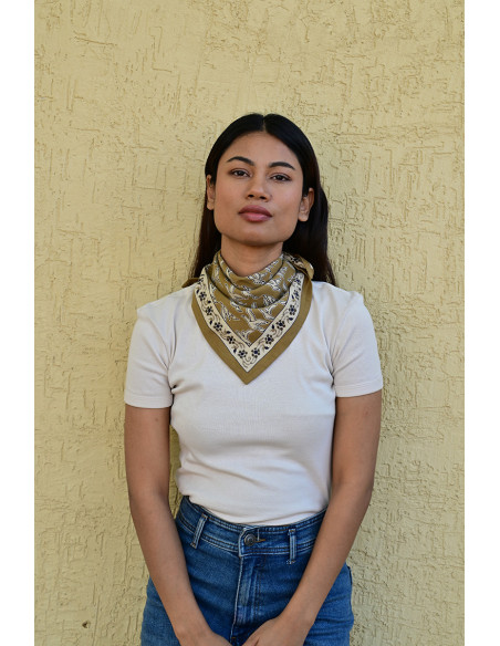 Femme portant le petit foulard Mercure Bistre 50x50 cm noué autour du cou.