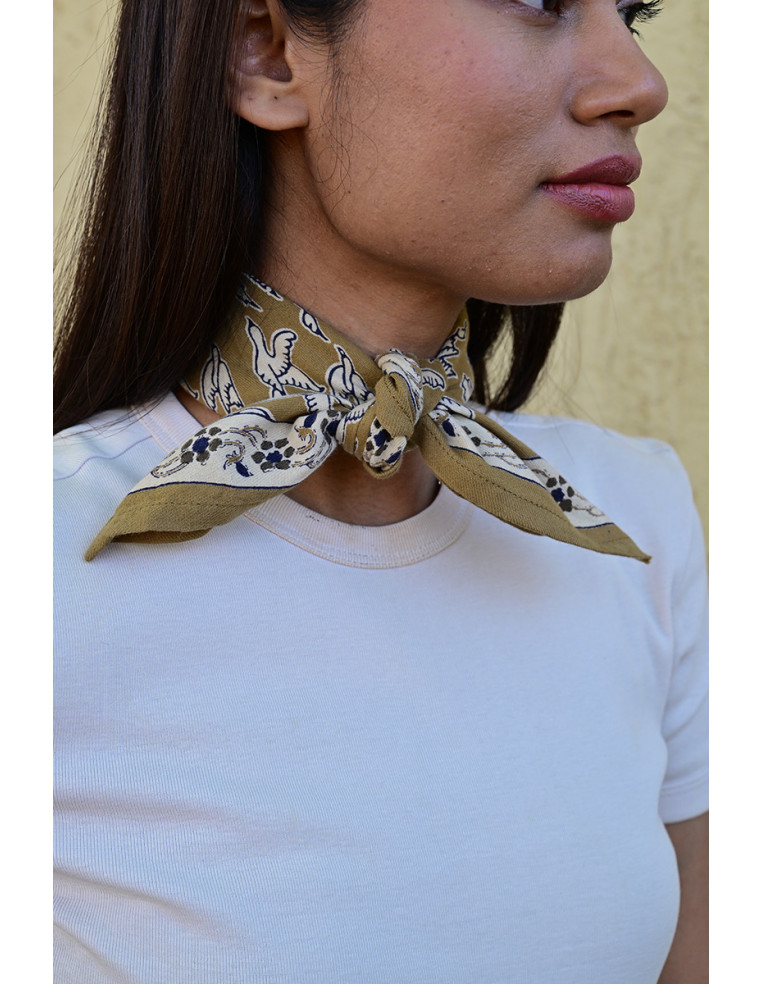 Femme portant le petit foulard Mercure Bistre 50x50 cm noué autour du cou.