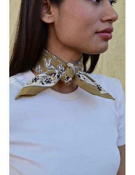 Femme portant le petit foulard Mercure Bistre 50x50 cm noué autour du cou.