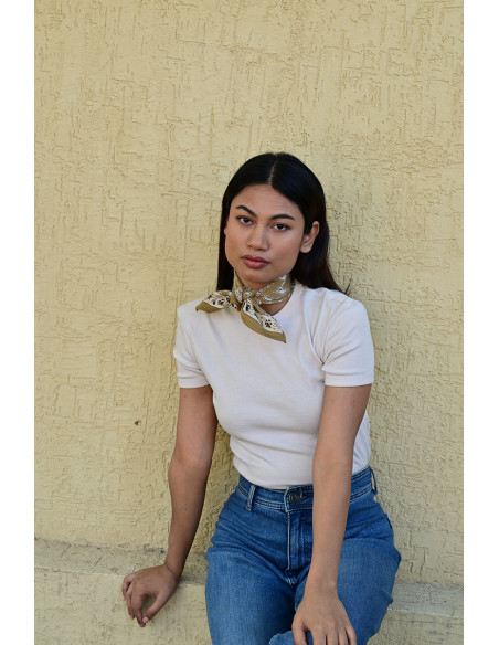 Femme portant le petit foulard Mercure Bistre 50x50 cm noué autour du cou.