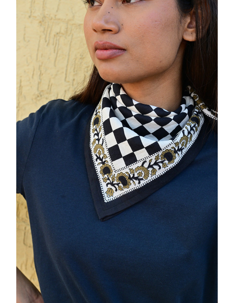 Gros plan sur la bordure florale imprimée au tampon de bois sur fond damier.