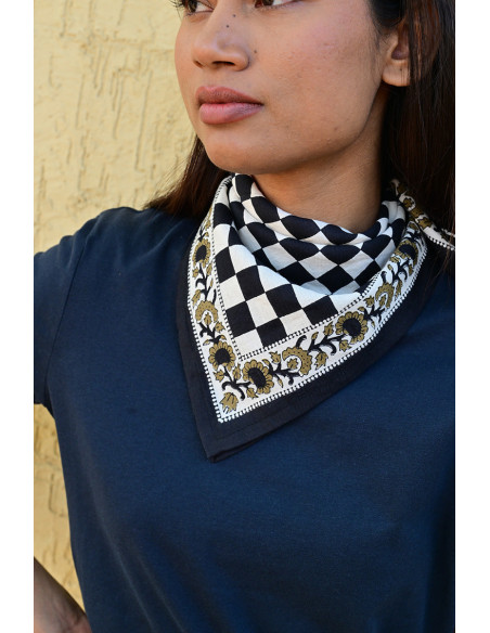 Gros plan sur la bordure florale imprimée au tampon de bois sur fond damier.