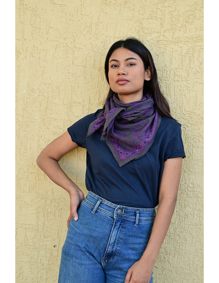 Femme portant le grand foulard Mercure Grisaille 100x100 cm noué autour du cou.
