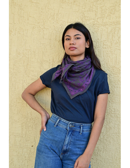 Femme portant le grand foulard Mercure Grisaille 100x100 cm noué autour du cou.