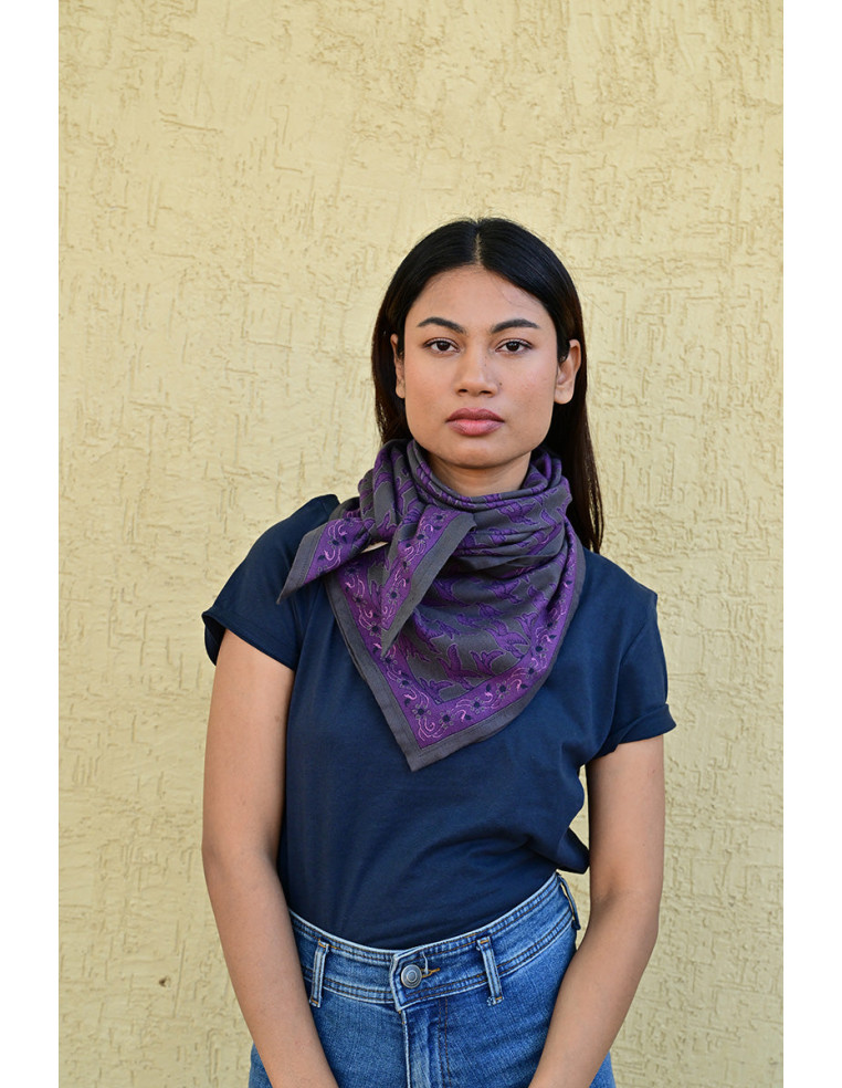 Femme portant le grand foulard Mercure Grisaille 100x100 cm noué autour du cou.