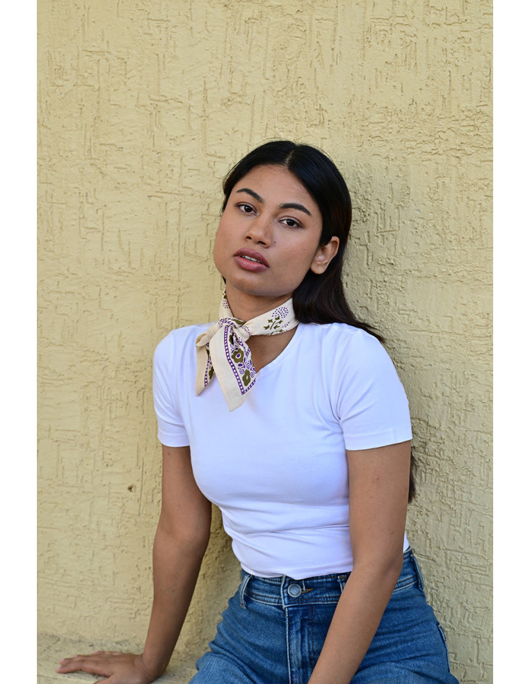 Femme portant le petit foulard Anastase latte 50x50 cm noué autour du cou.