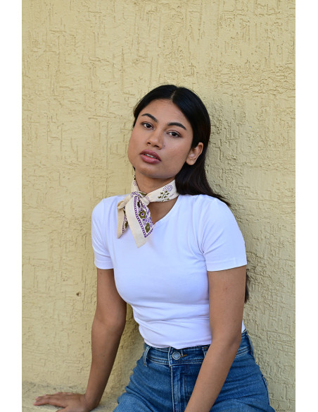 Femme portant le petit foulard Anastase latte 50x50 cm noué autour du cou.