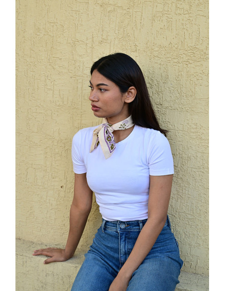 Femme portant le petit foulard Anastase latte 50x50 cm noué autour du cou.