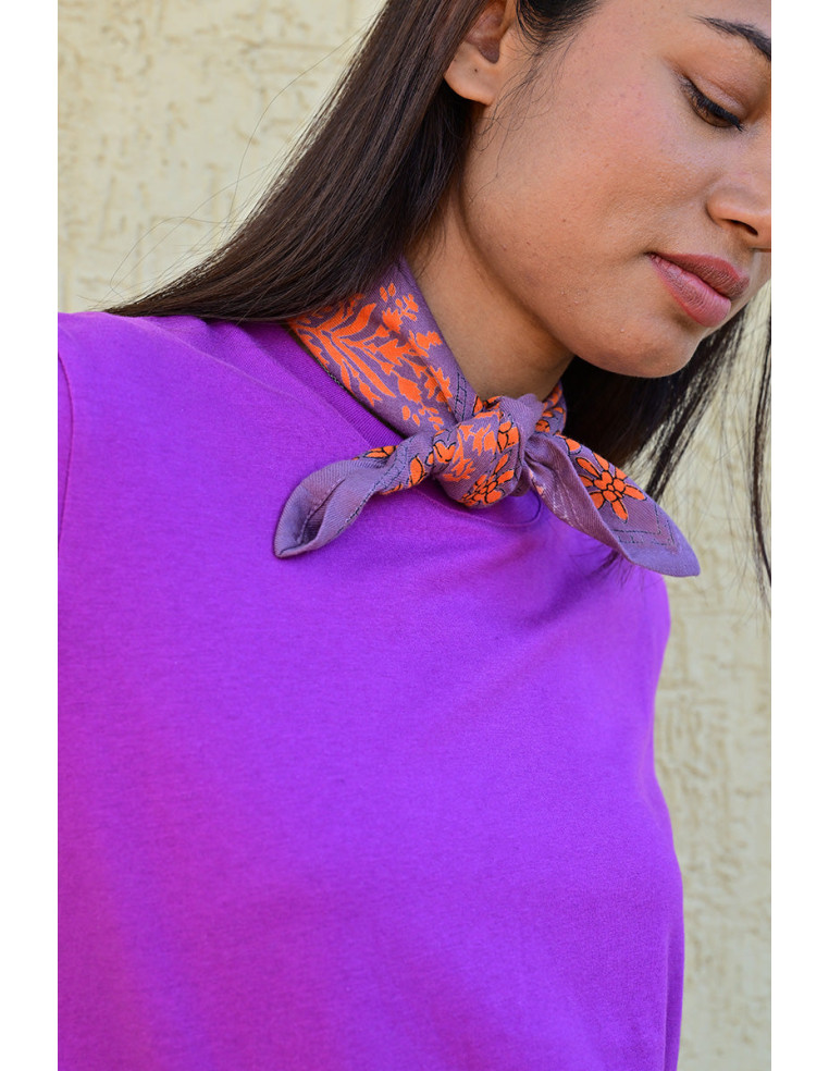 Bandana Galatie motifs floraux oranges porté noué autour du cou.