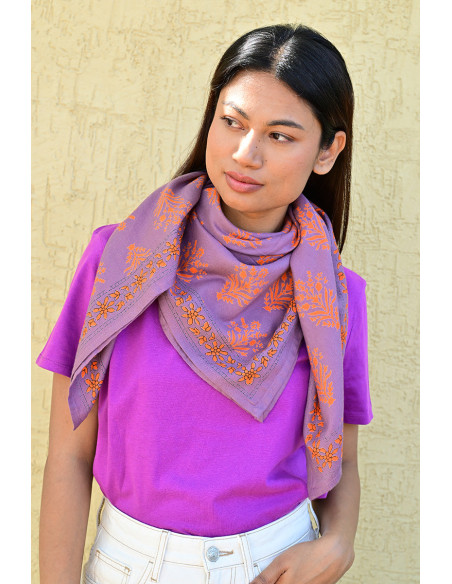 Bandana Galatie motifs floraux oranges porté autour du cou.